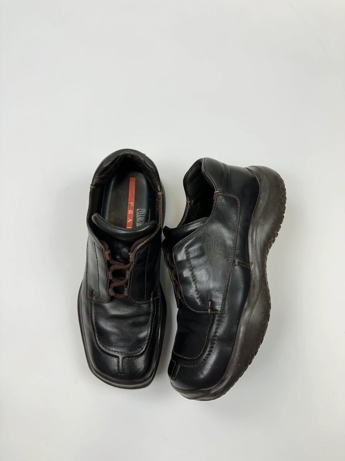 Prada black leather Derby shoes with Vibram sole and Linearossa logo detail.