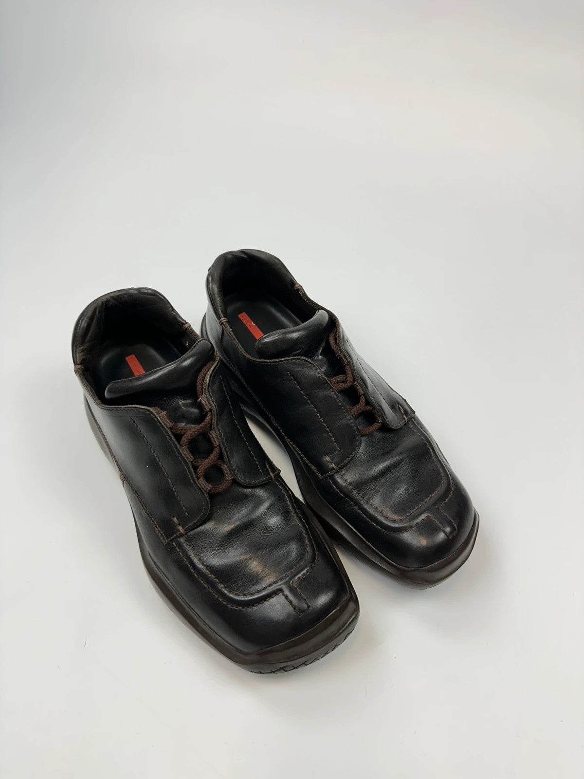 Prada black leather Derby shoes with Vibram sole and Linearossa logo detail.