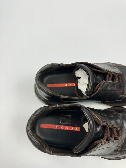 Prada black leather Derby shoes with Vibram sole and Linearossa logo detail.