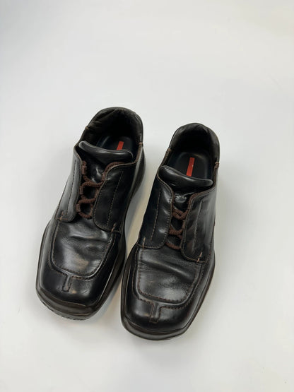 Prada black leather Derby shoes with Vibram sole and Linearossa logo detail.