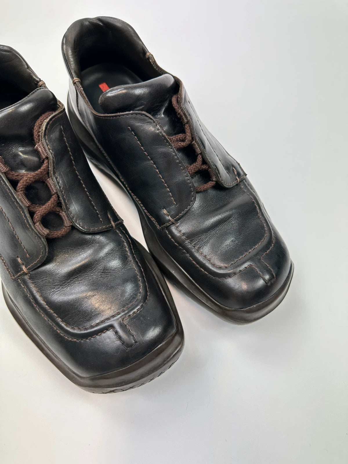 Prada black leather Derby shoes with Vibram sole and Linearossa logo detail.