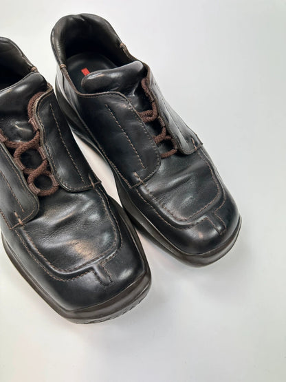 Prada black leather Derby shoes with Vibram sole and Linearossa logo detail.