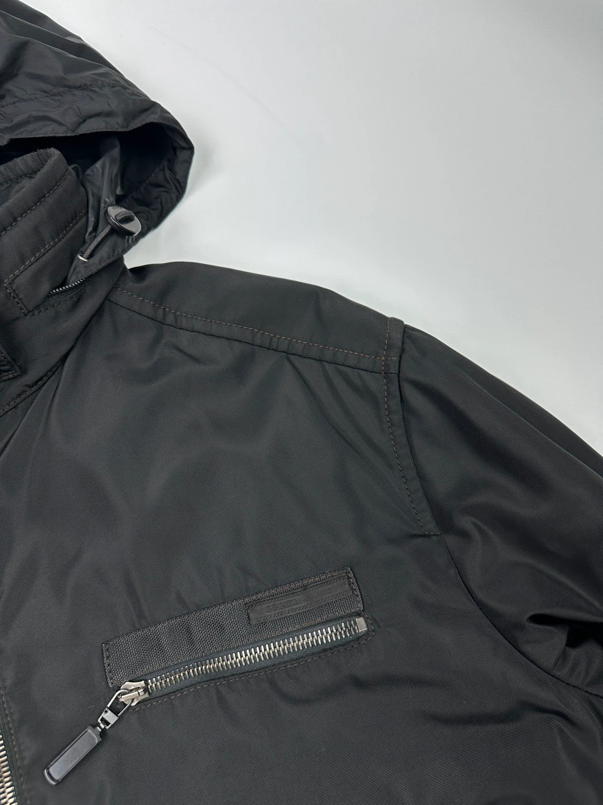Prada black bomber jacket with hidden hood, minimalist design, luxury runway archive.