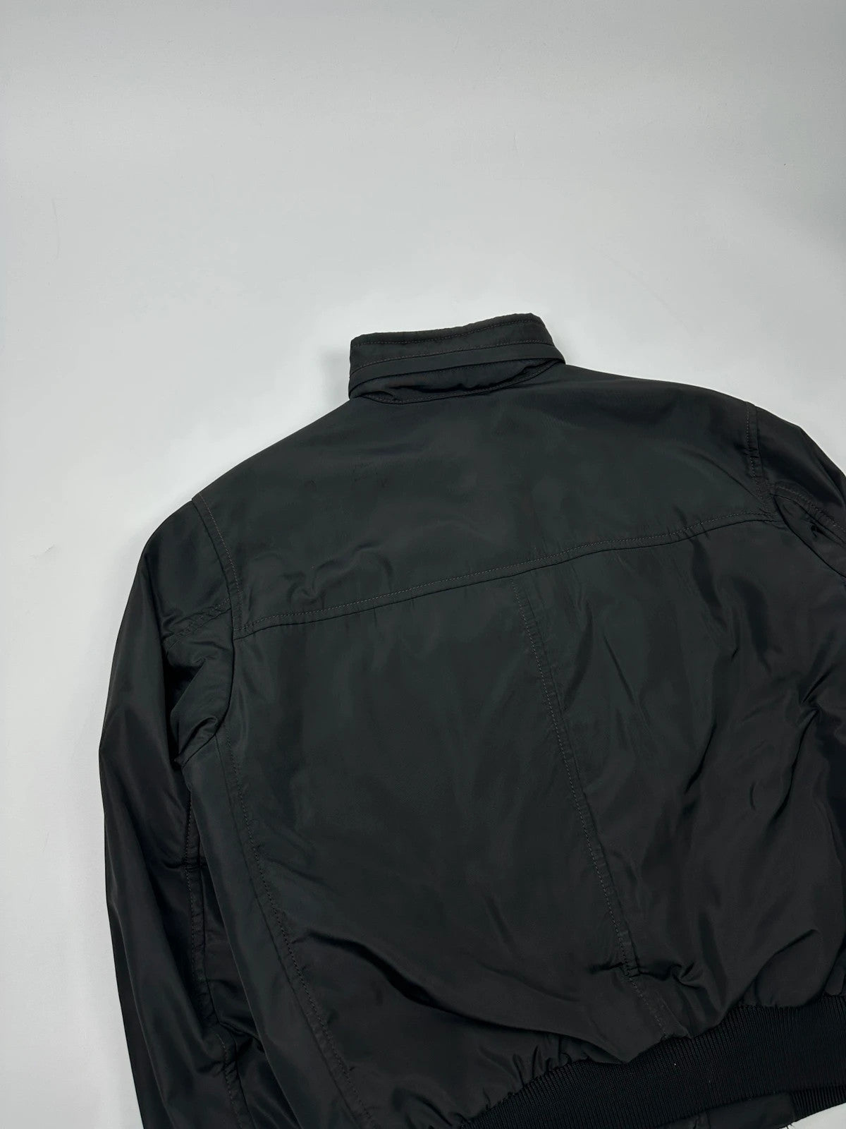 Prada black bomber jacket with hidden hood, minimalist design, luxury runway archive.
