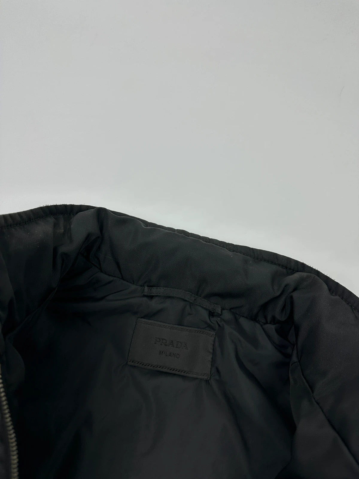 Prada black bomber jacket with hidden hood, minimalist design, luxury runway archive.