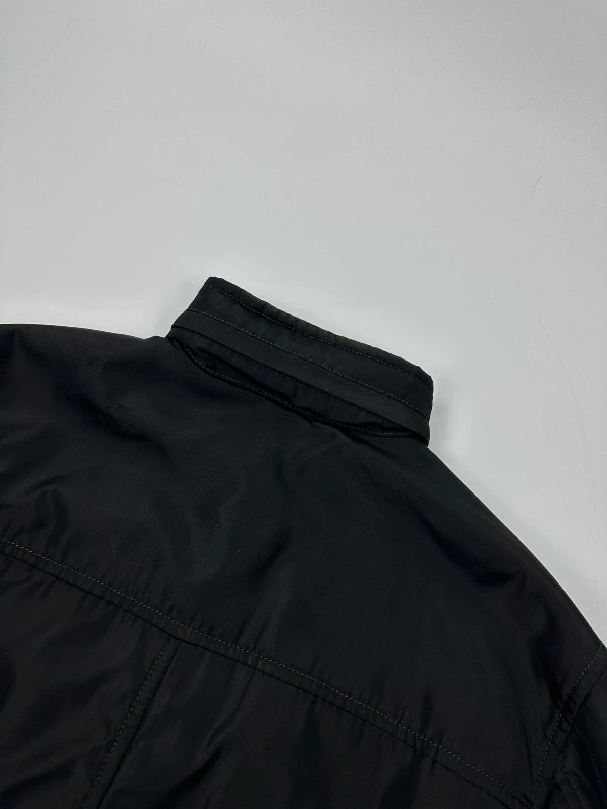 Prada black bomber jacket with hidden hood, minimalist design, luxury runway archive.