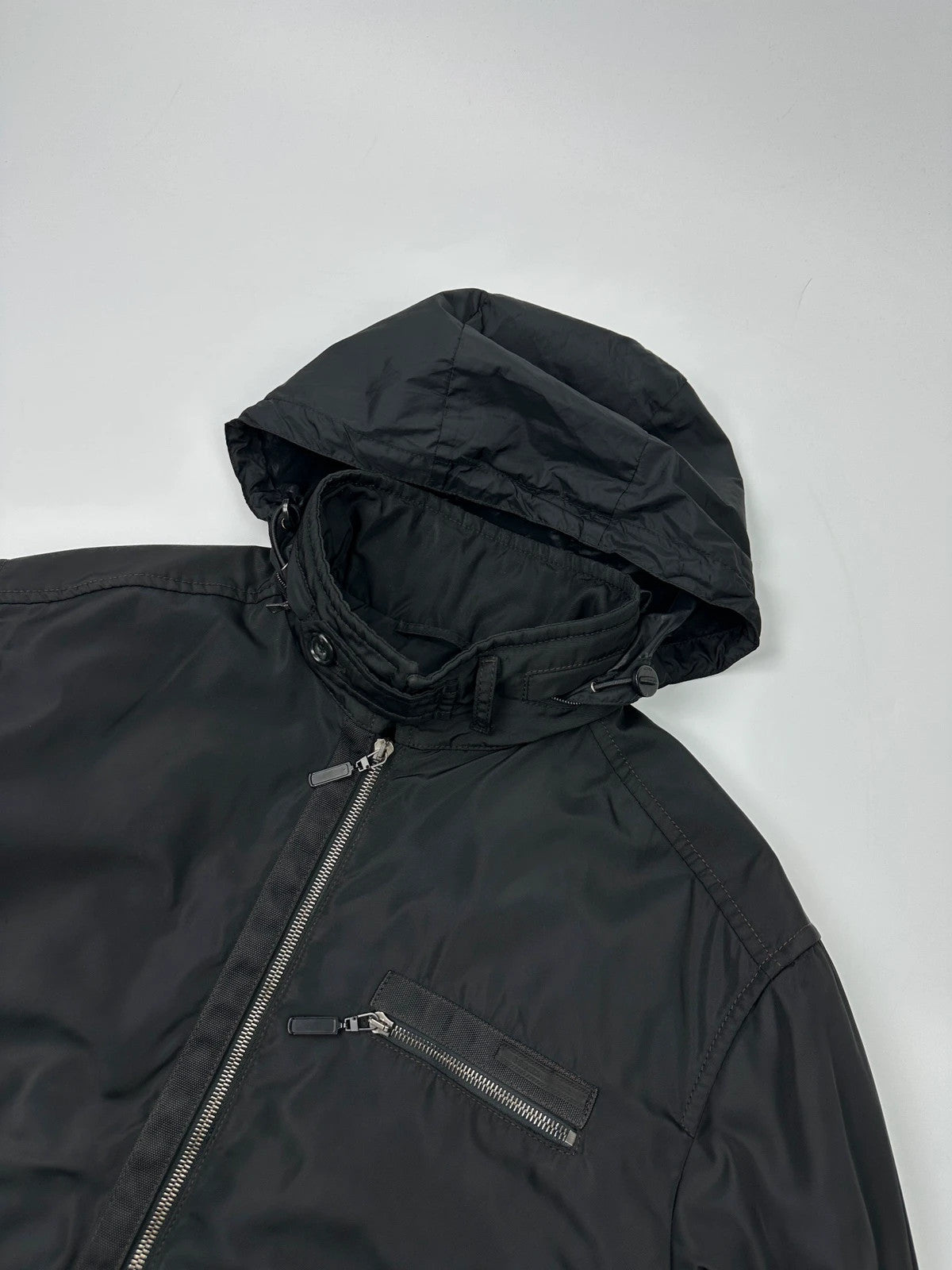 Prada black bomber jacket with hidden hood, minimalist design, luxury runway archive.