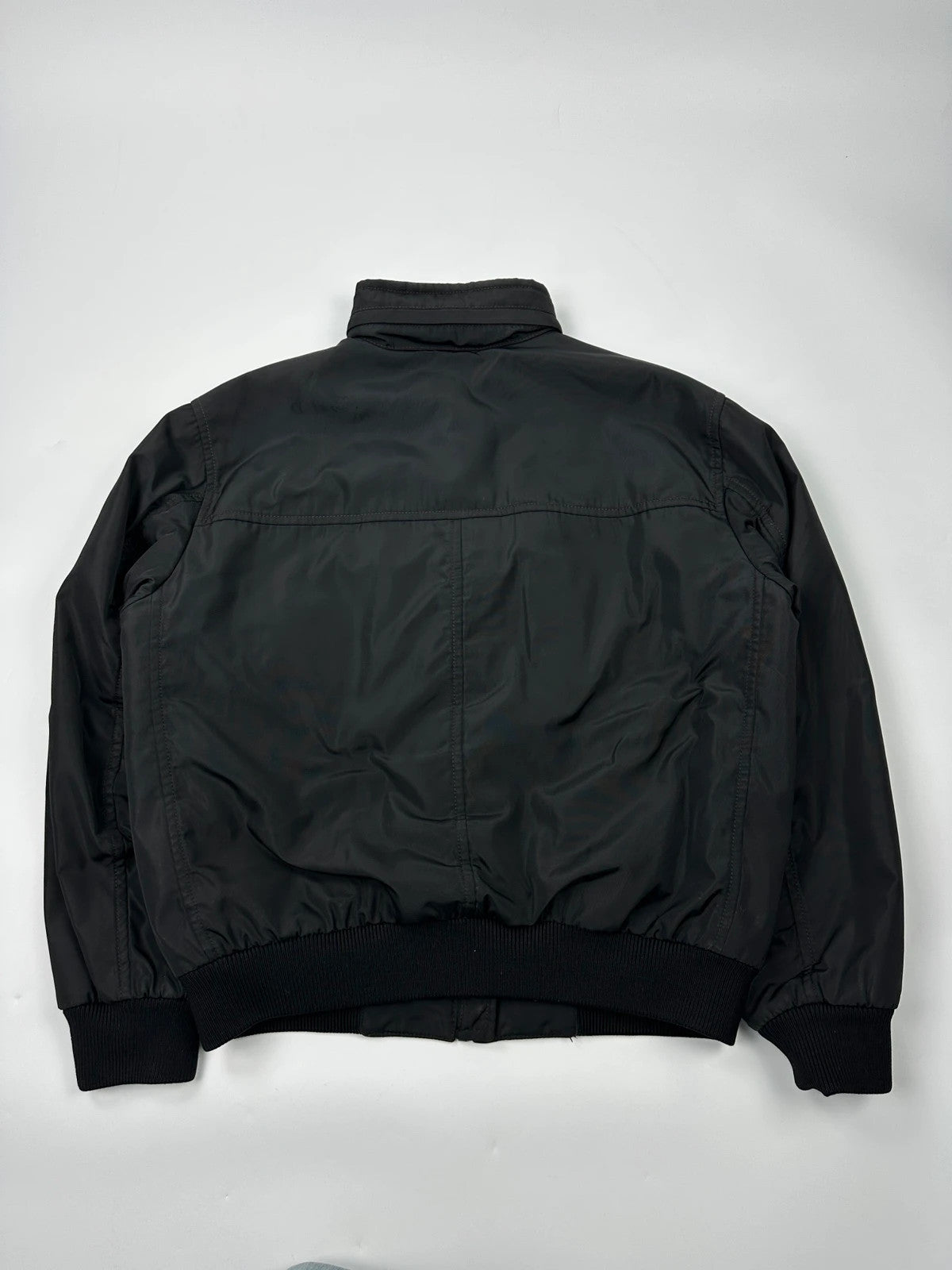 Prada black bomber jacket with hidden hood, minimalist design, luxury runway archive.