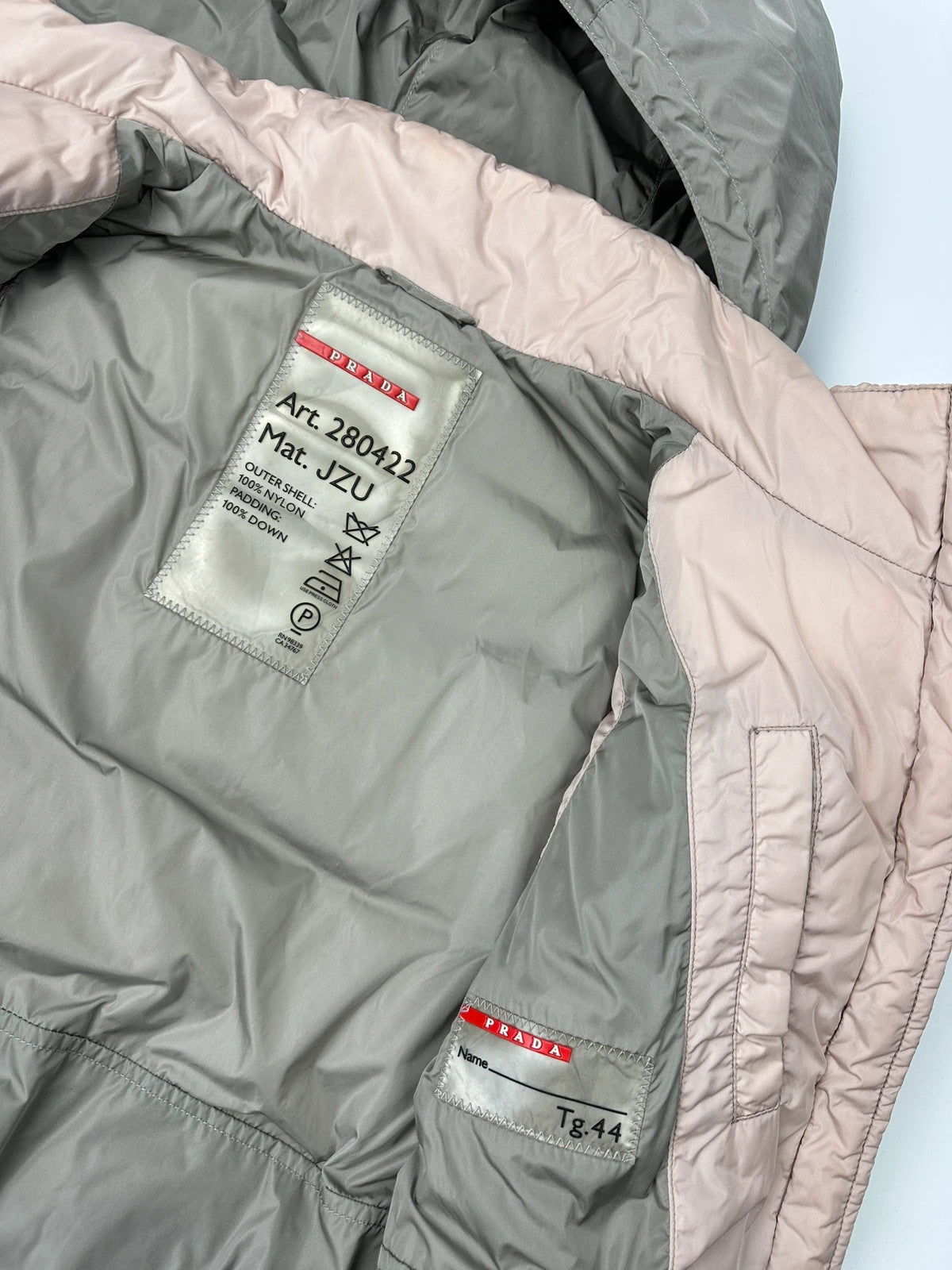 Prada orange and pink puffer vest with retractable hood and logo detailing.