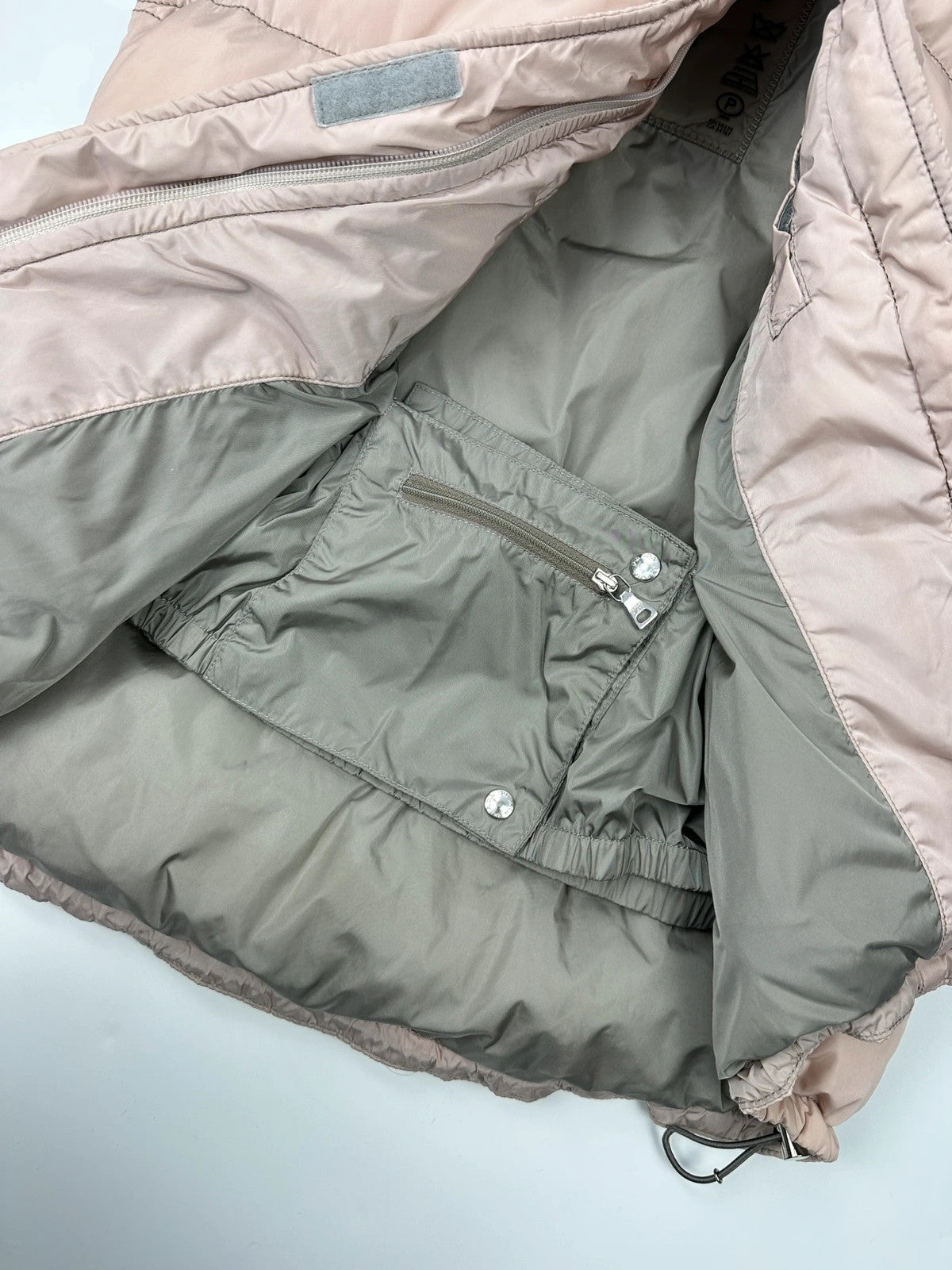 Prada orange and pink puffer vest with retractable hood and logo detailing.