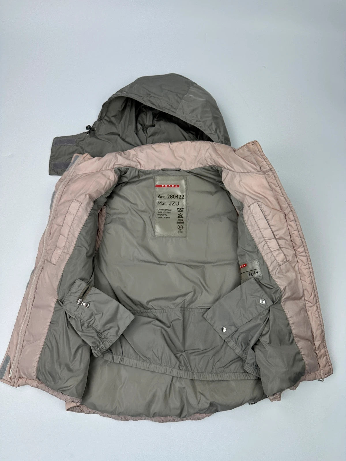Prada orange and pink puffer vest with retractable hood and logo detailing.