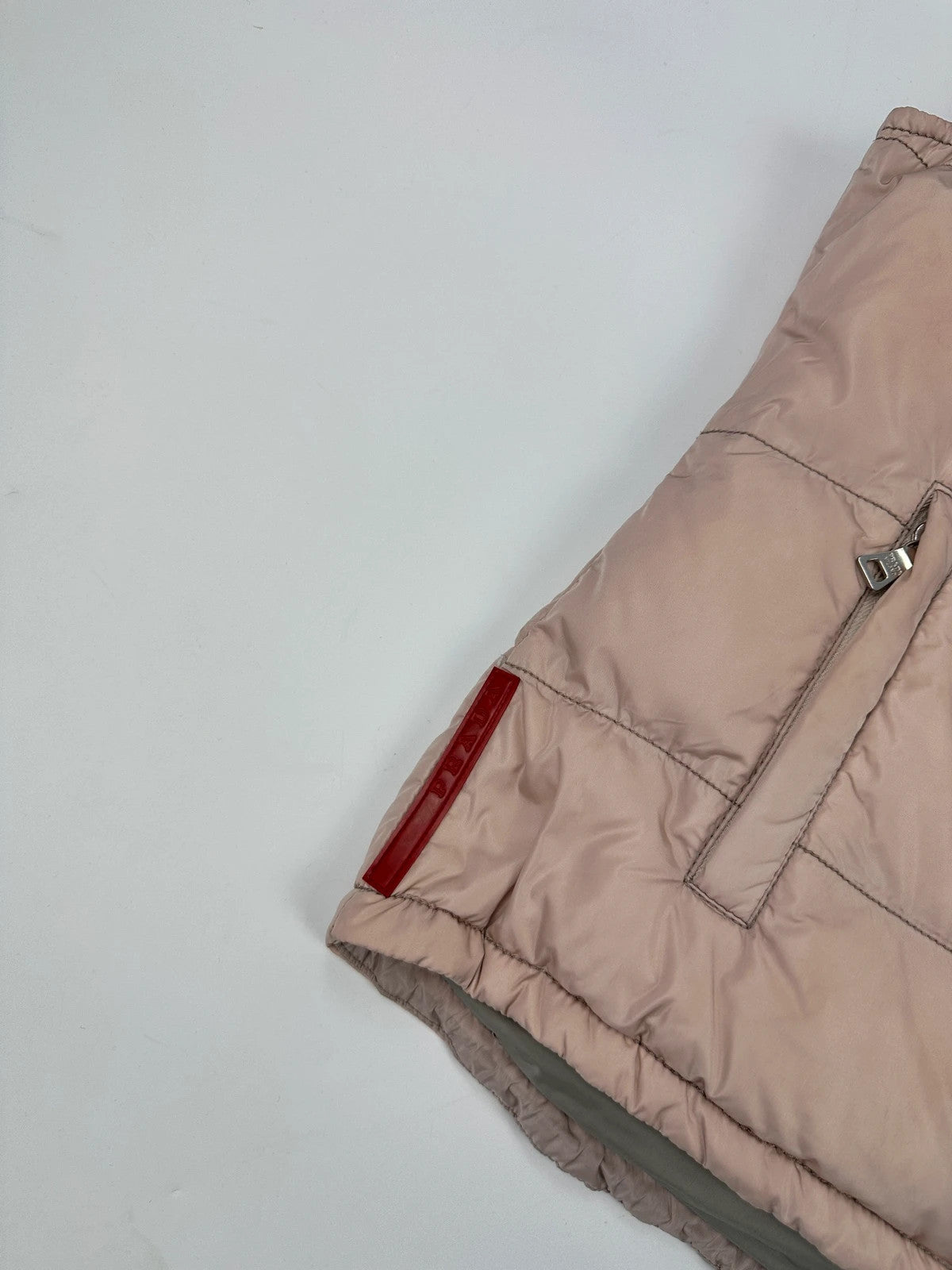 Prada orange and pink puffer vest with retractable hood and logo detailing.