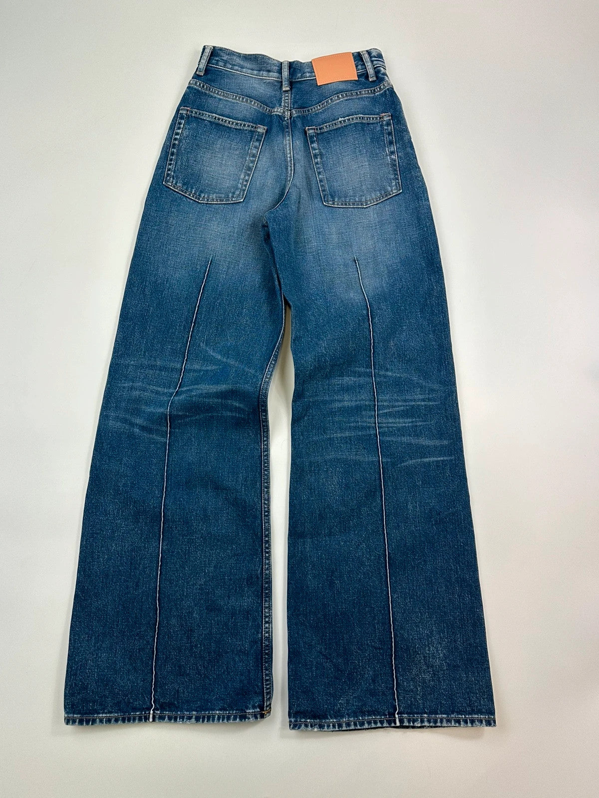 Acne Studios blue wide leg denim pants with subtle logo detailing and vintage style.