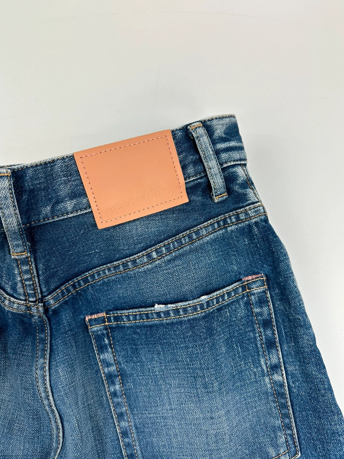 Acne Studios blue wide leg denim pants with subtle logo detailing and vintage style.