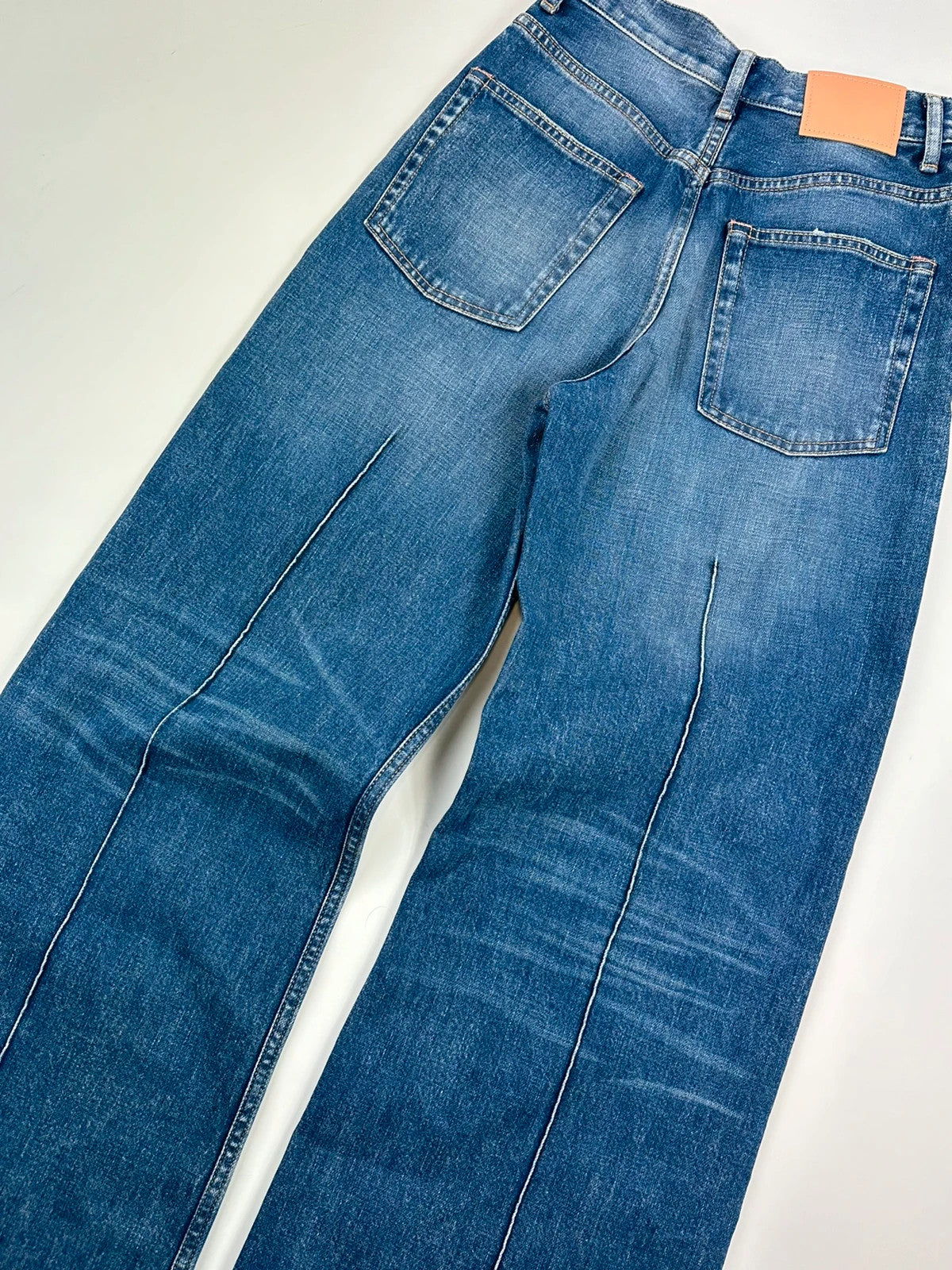 Acne Studios blue wide leg denim pants with subtle logo detailing and vintage style.