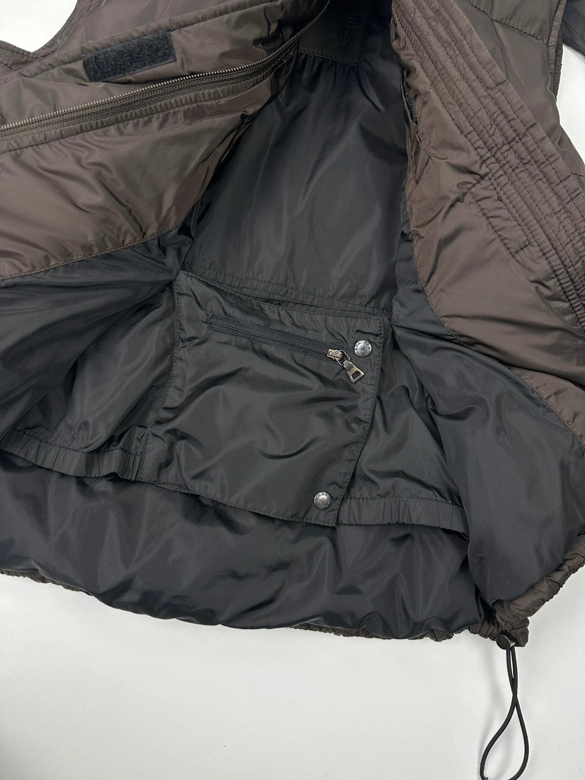 Prada brown puffer vest with retractable hood and linearossa logo details.