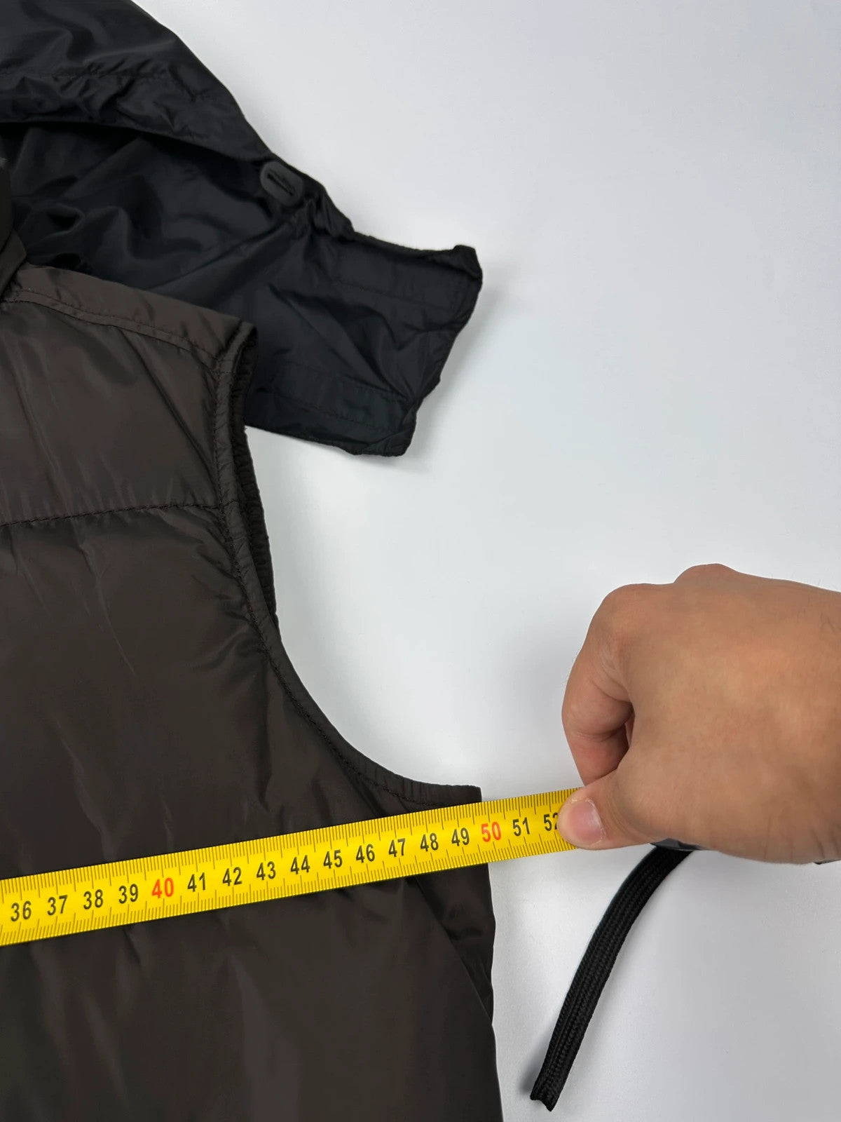 Prada brown puffer vest with retractable hood and linearossa logo details.