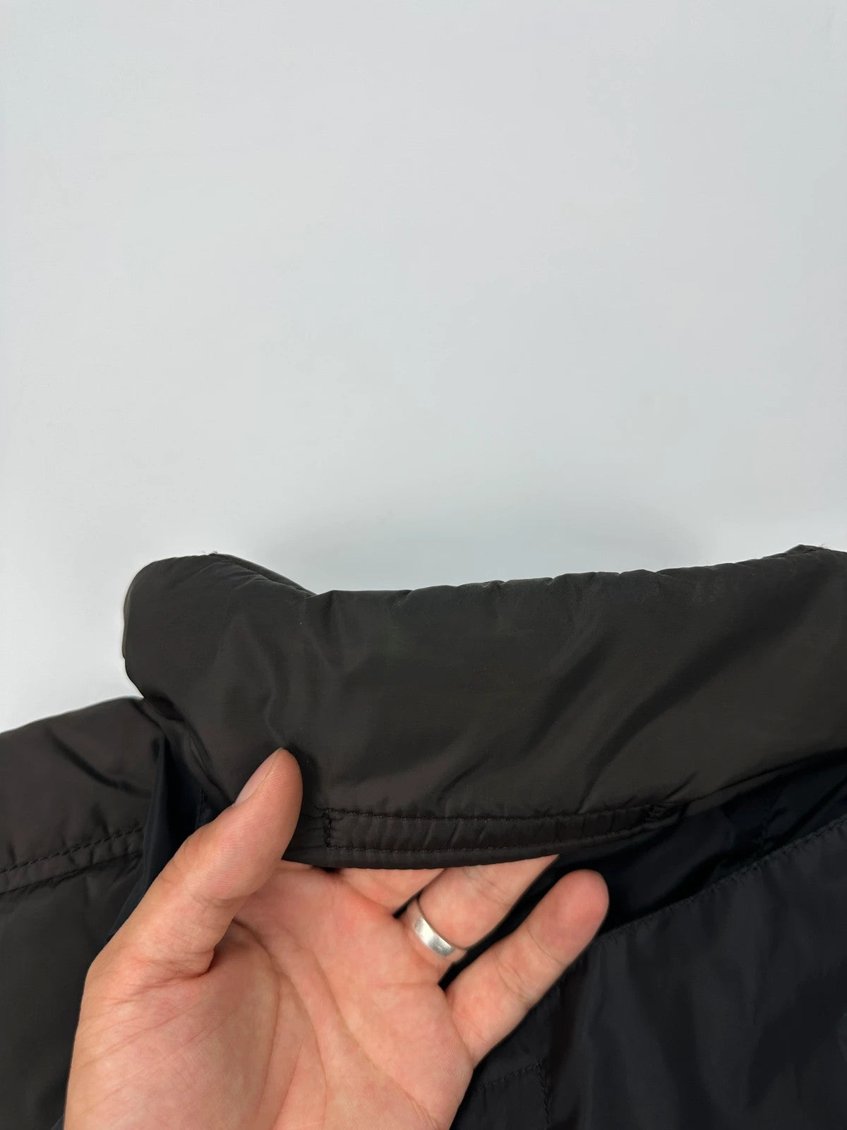 Prada brown puffer vest with retractable hood and linearossa logo details.