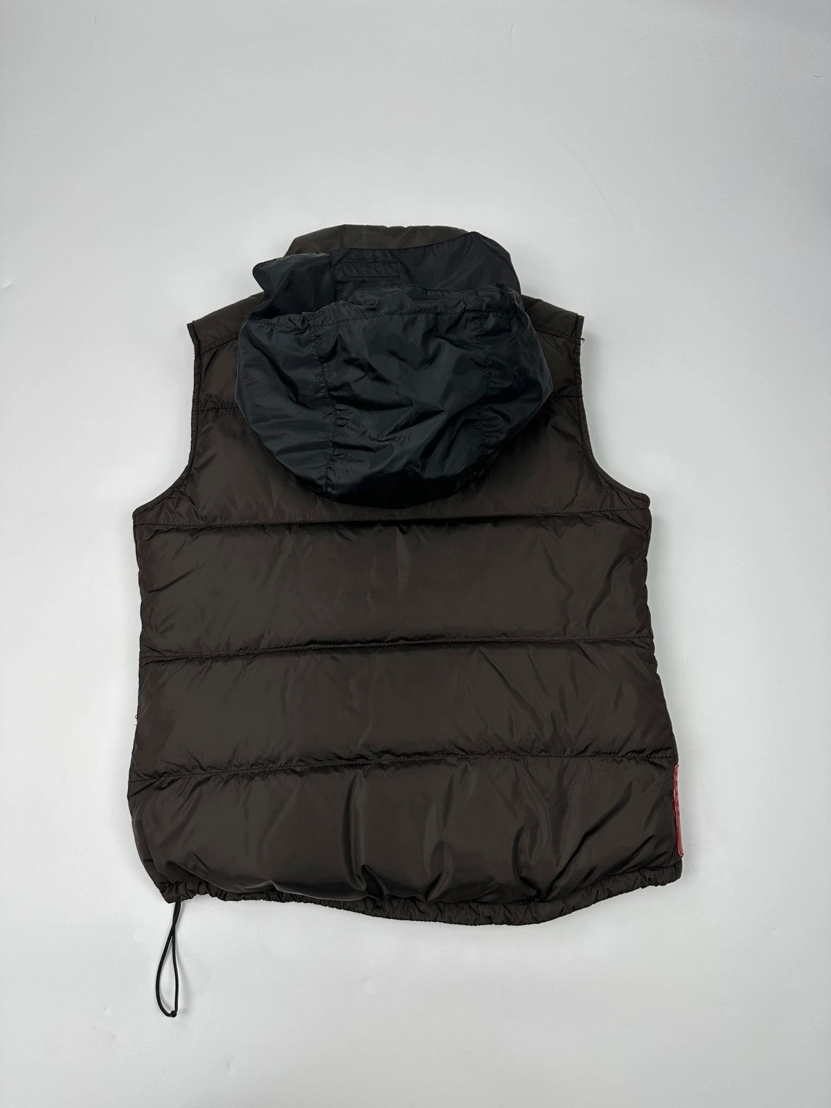 Prada brown puffer vest with retractable hood and linearossa logo details.