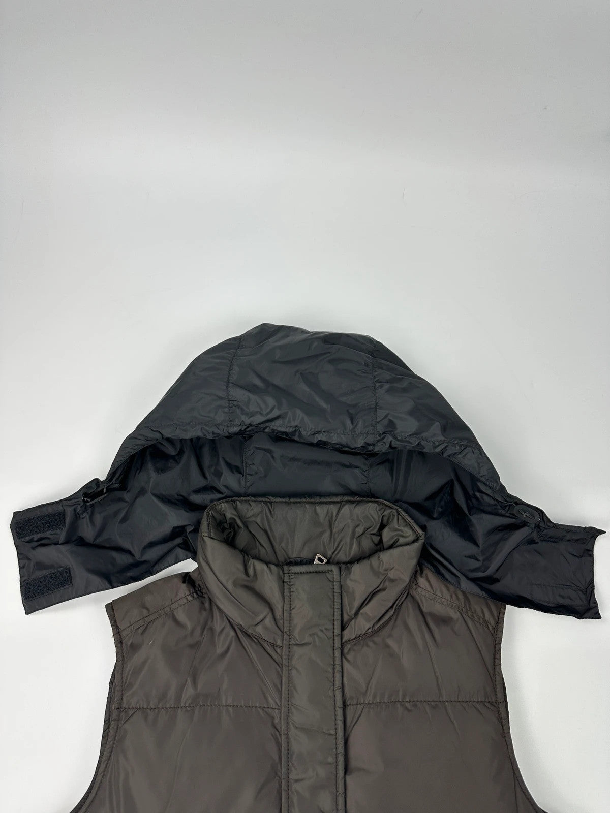 Prada brown puffer vest with retractable hood and linearossa logo details.