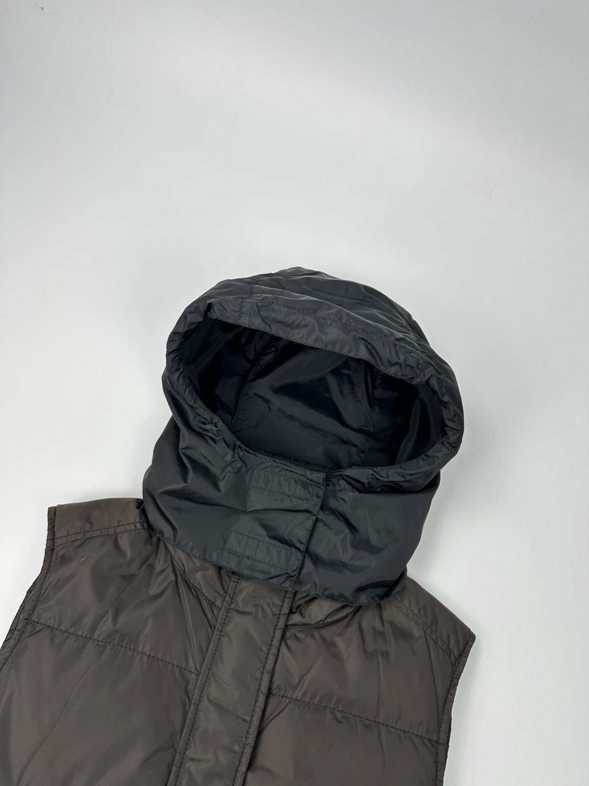 Prada brown puffer vest with retractable hood and linearossa logo details.