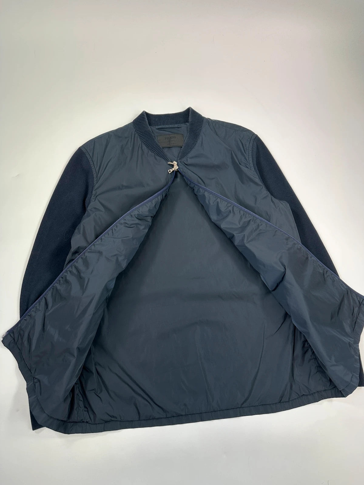 Prada navy blue hybrid jacket with nylon front and cotton sleeves, minimalist design.