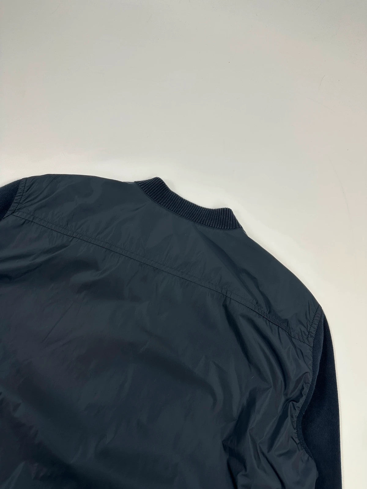 Prada navy blue hybrid jacket with nylon front and cotton sleeves, minimalist design.