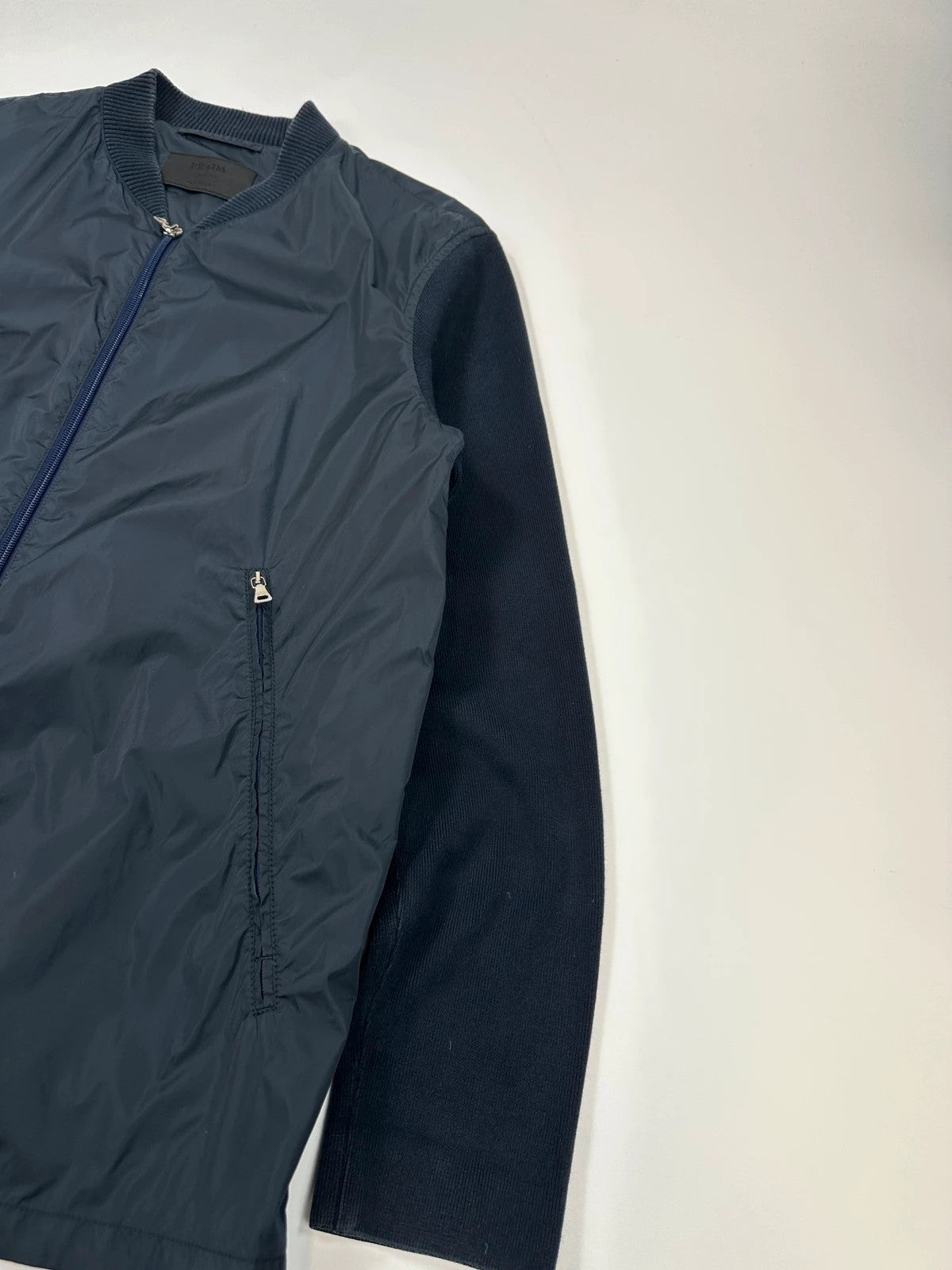 Prada navy blue hybrid jacket with nylon front and cotton sleeves, minimalist design.