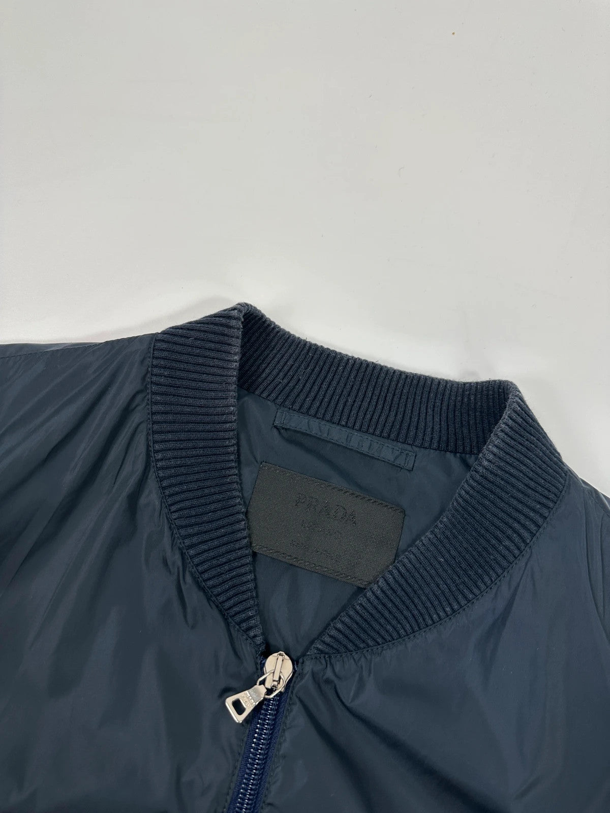 Prada navy blue hybrid jacket with nylon front and cotton sleeves, minimalist design.