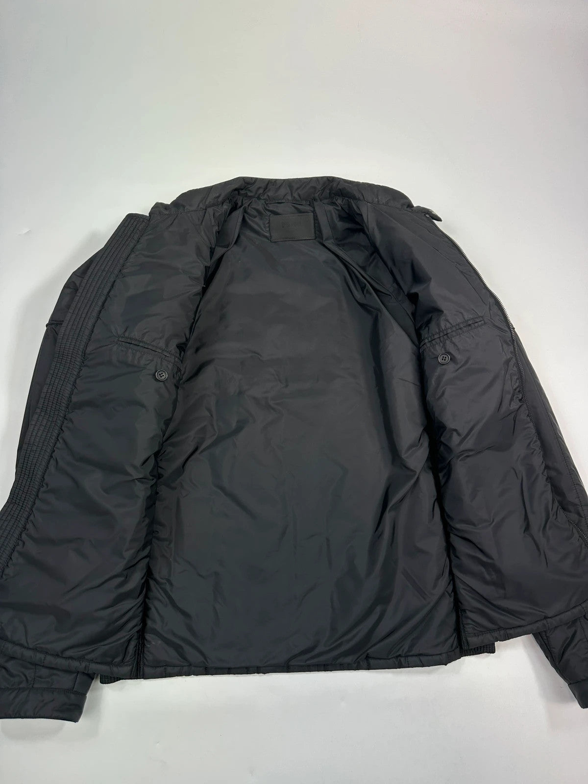 Prada black padded quilted nylon jacket with ribbed side panels and logo detailing.