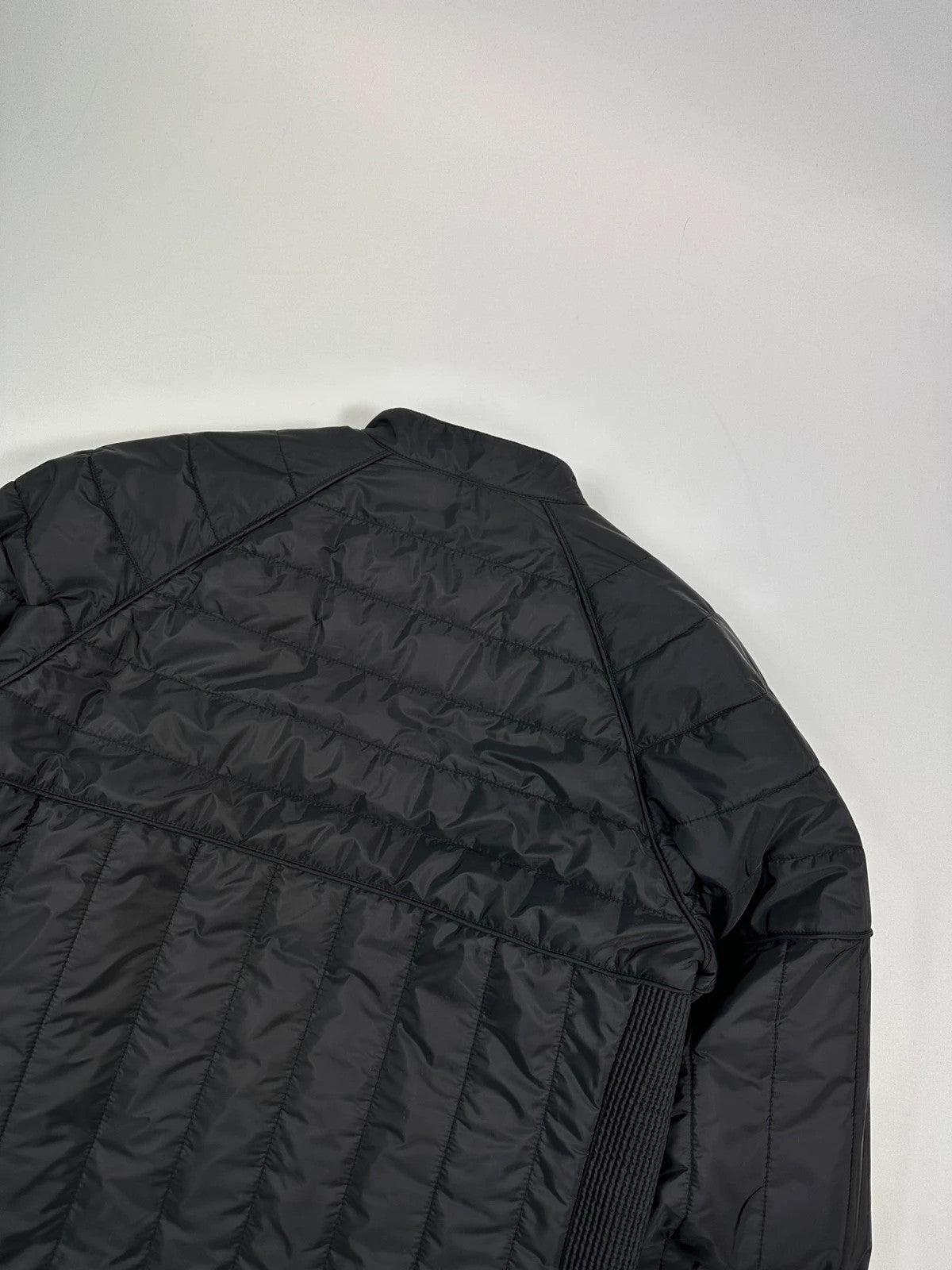 Prada black padded quilted nylon jacket with ribbed side panels and logo detailing.
