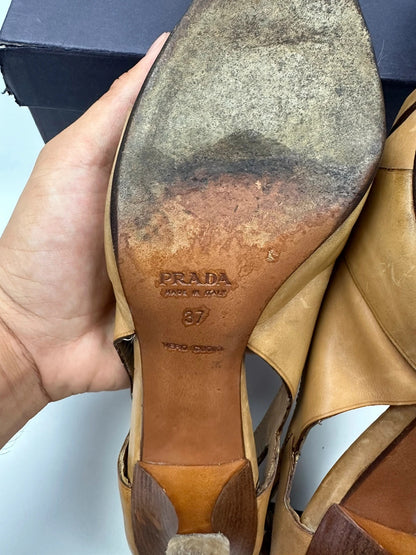 Prada beige leather pumps with pointy toe and subtle logo detailing.