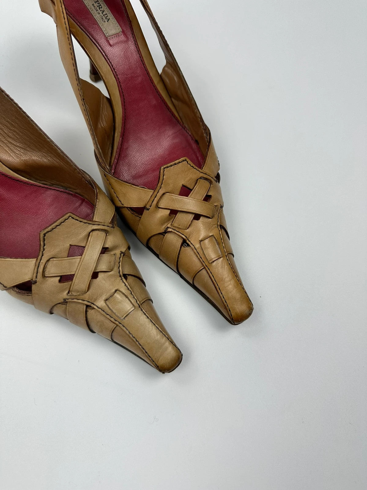Prada beige leather pumps with pointy toe and subtle logo detailing.
