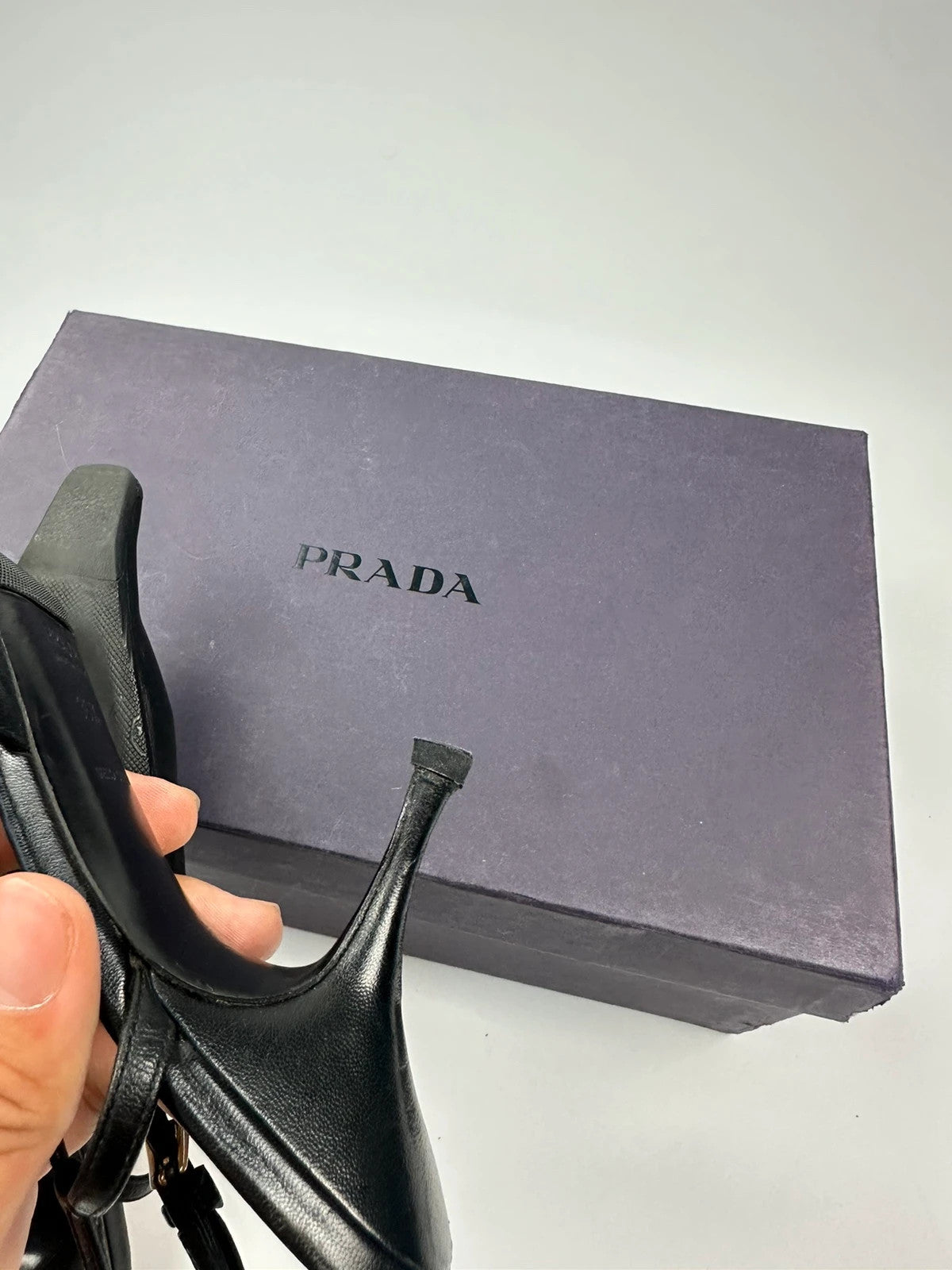 Prada black leather slingback mules with minimalist design and logo detail.