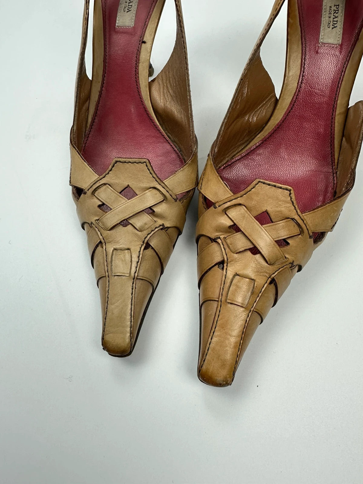 Prada beige leather pumps with pointy toe and subtle logo detailing.