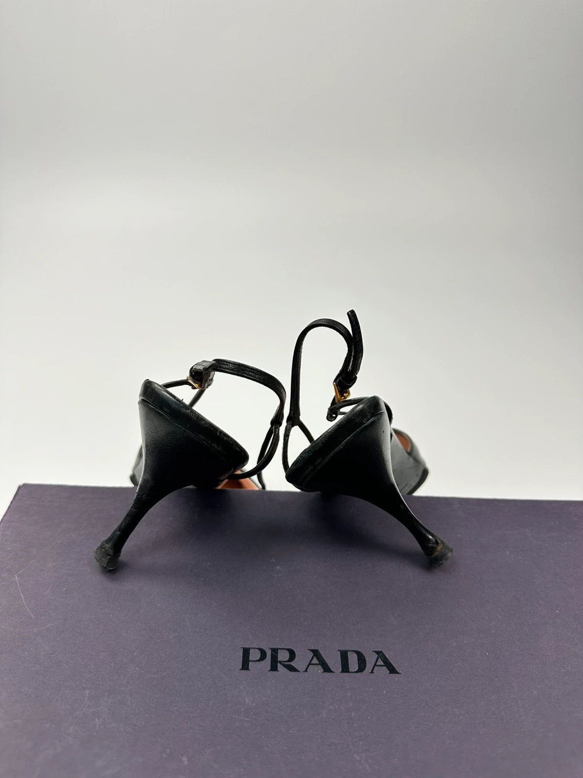 Prada black leather slingback mules with minimalist design and logo detail.