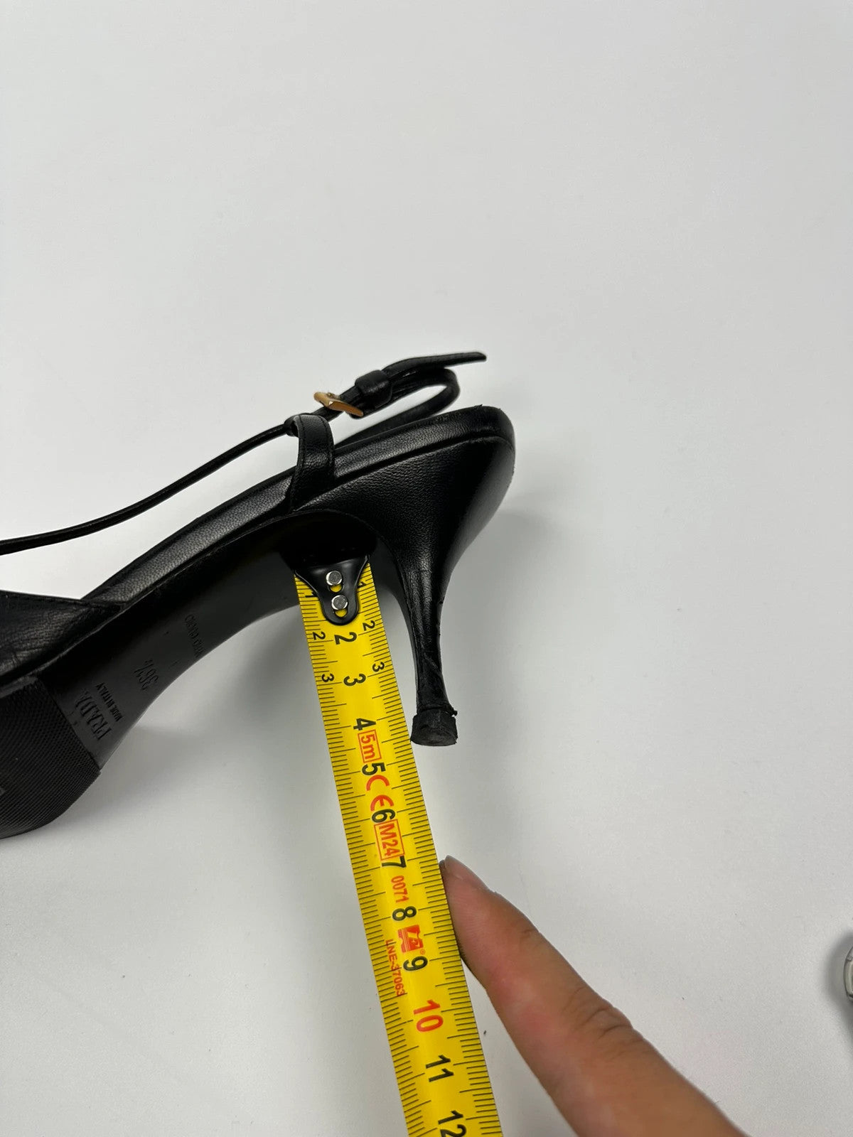 Prada black leather slingback mules with minimalist design and logo detail.