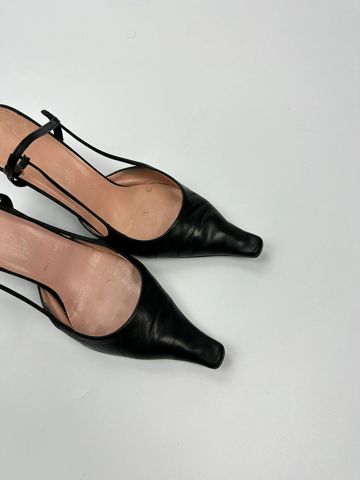Prada black leather slingback mules with minimalist design and logo detail.