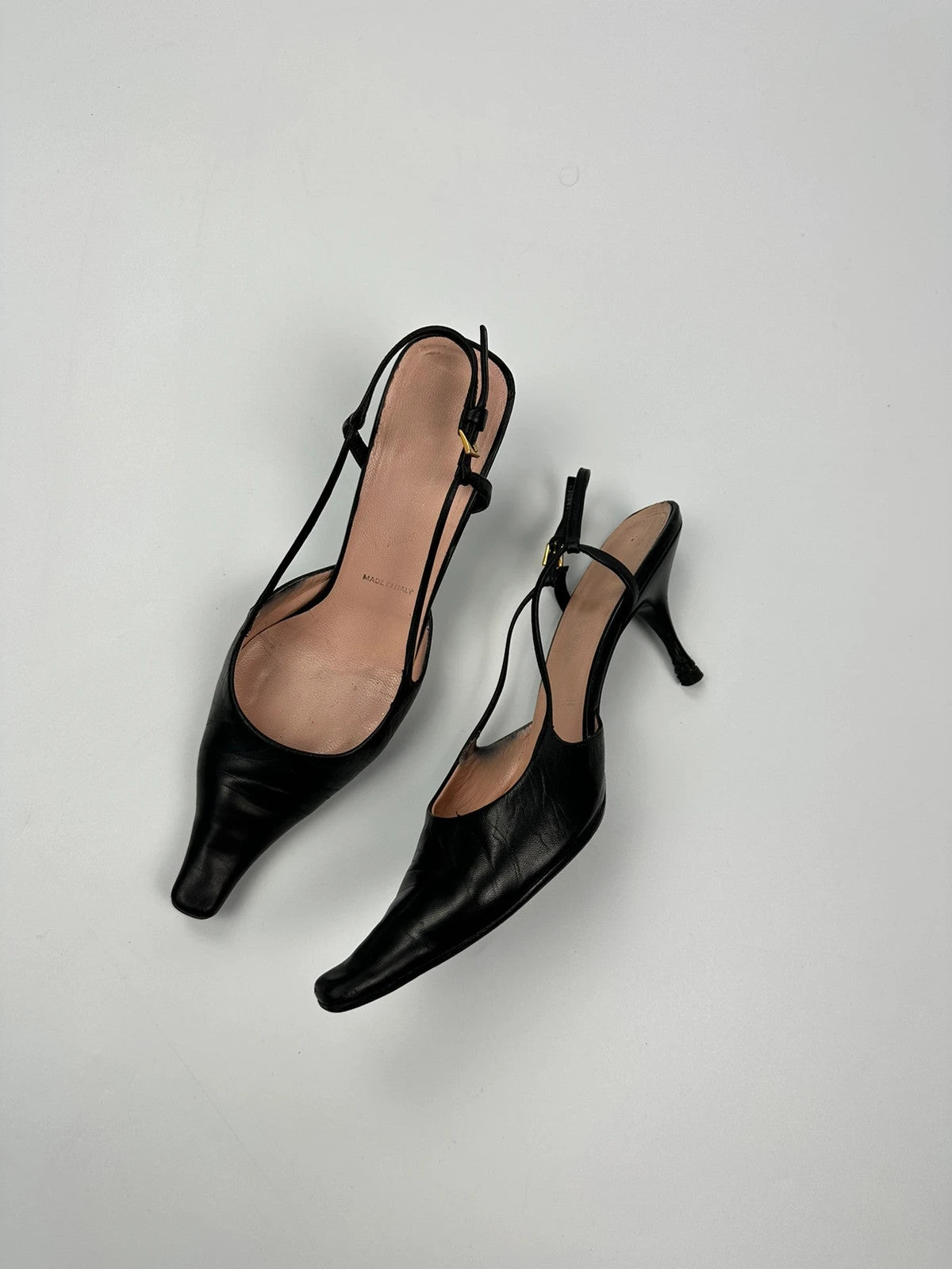 Prada black leather slingback mules with minimalist design and logo detail.