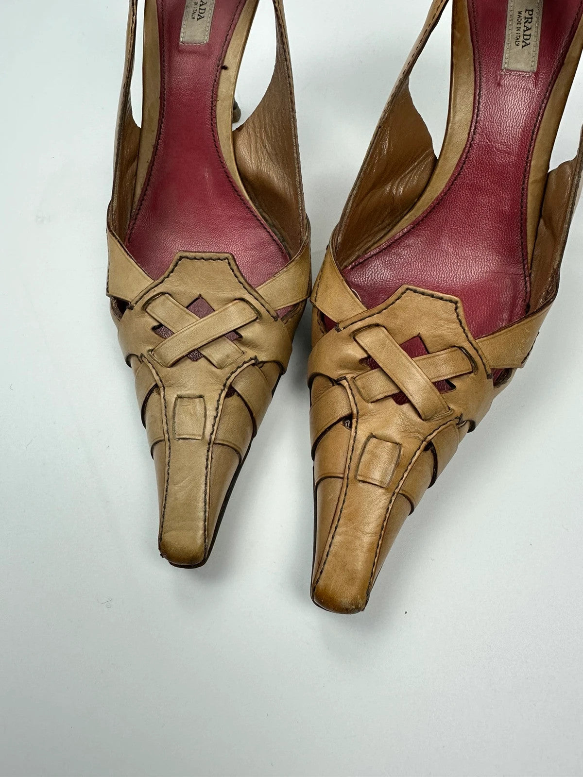 Prada beige leather pumps with pointy toe and subtle logo detailing.