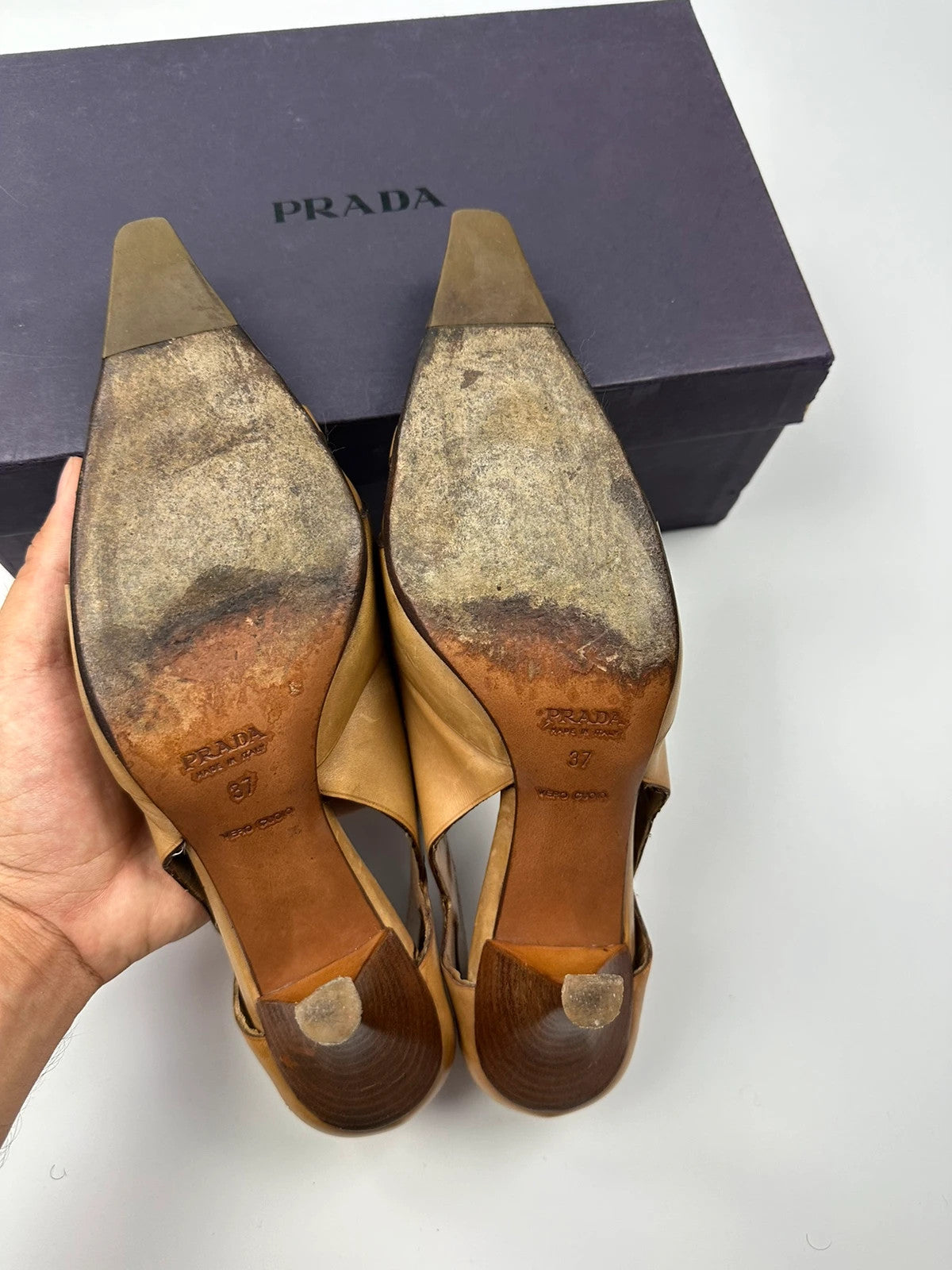 Prada beige leather pumps with pointy toe and subtle logo detailing.