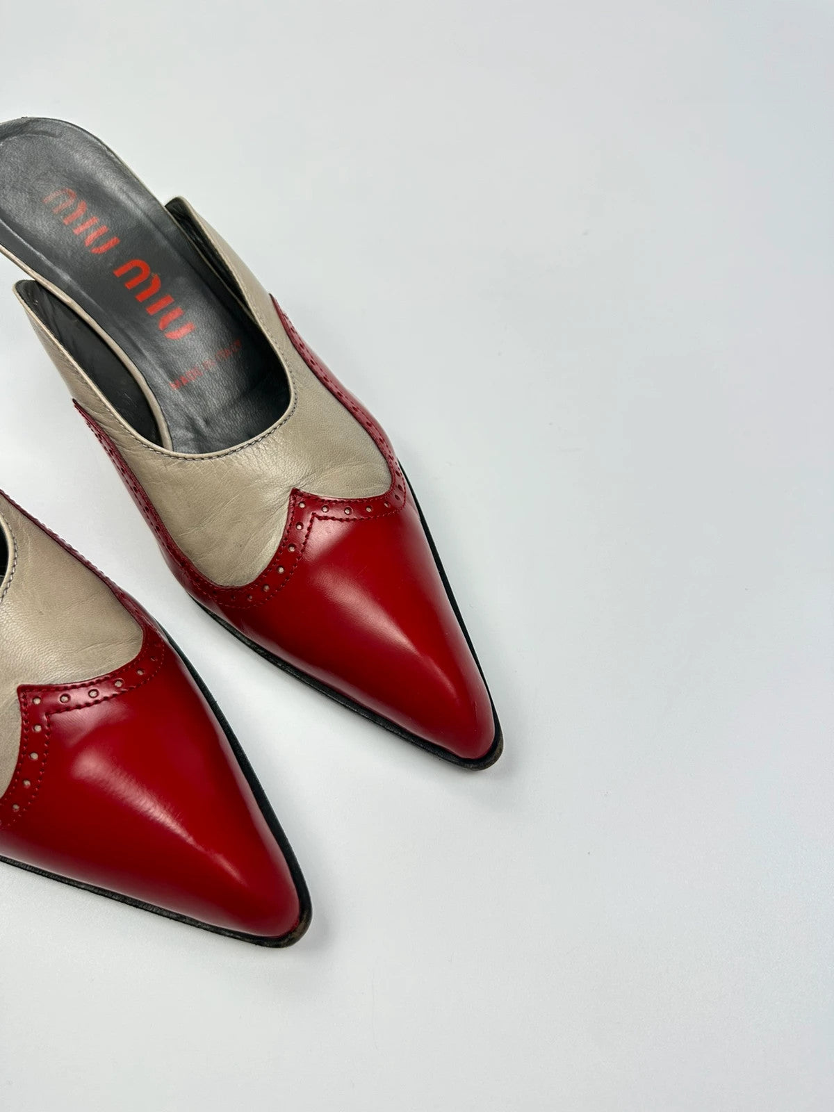 Miu Miu beige and red leather mules with kitten heels and minimalist design.