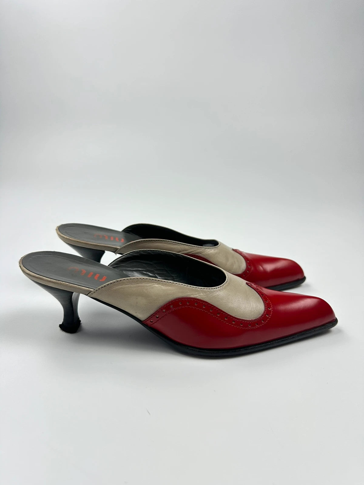 Miu Miu beige and red leather mules with kitten heels and minimalist design.