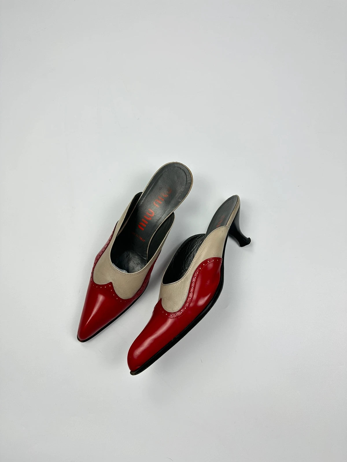 Miu Miu beige and red leather mules with kitten heels and minimalist design.