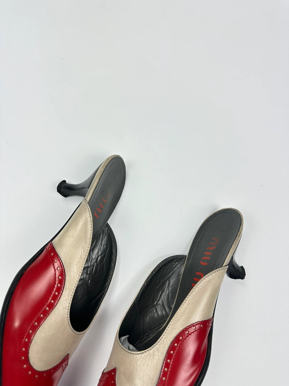 Miu Miu beige and red leather mules with kitten heels and minimalist design.