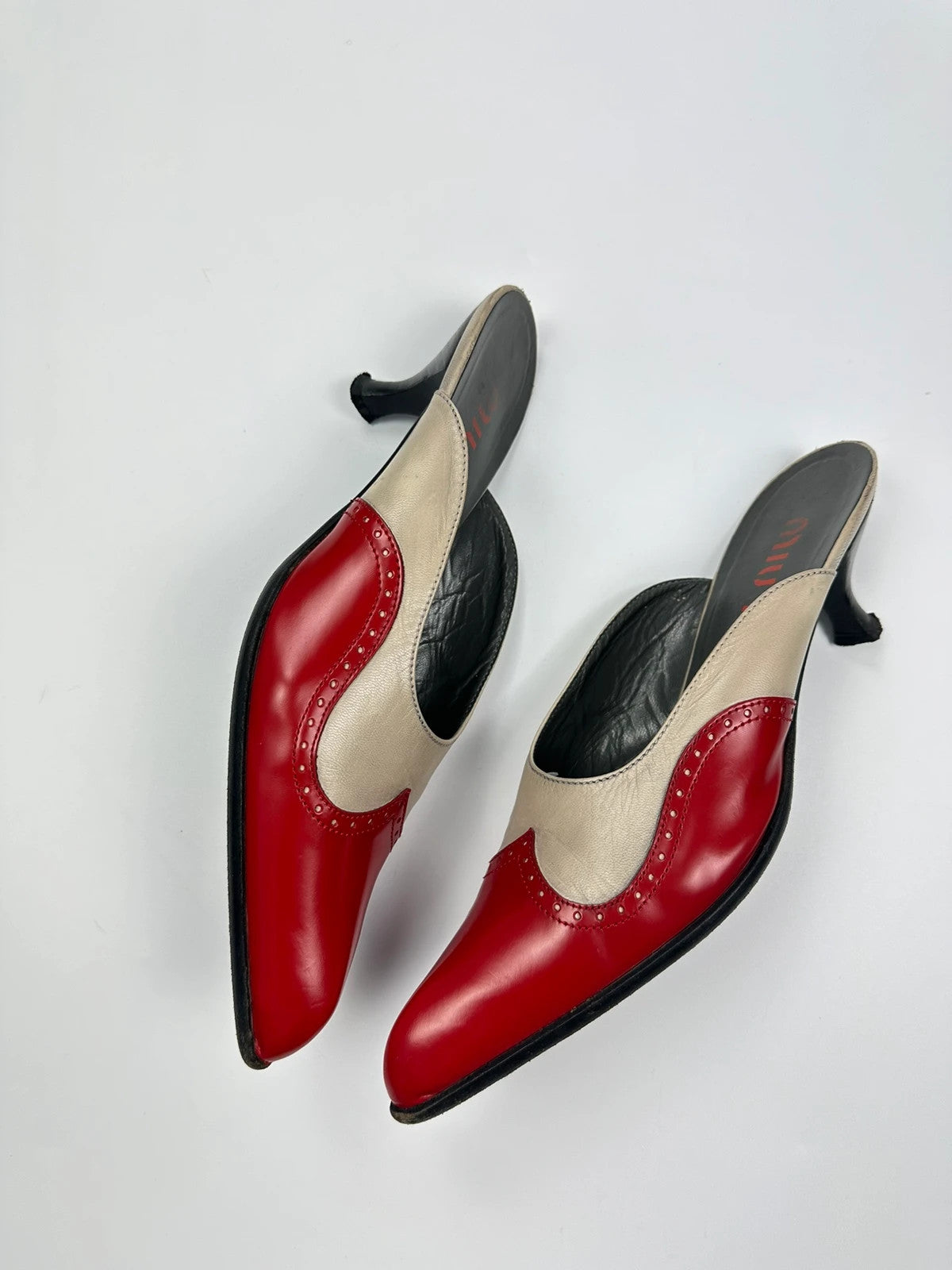 Miu Miu beige and red leather mules with kitten heels and minimalist design.