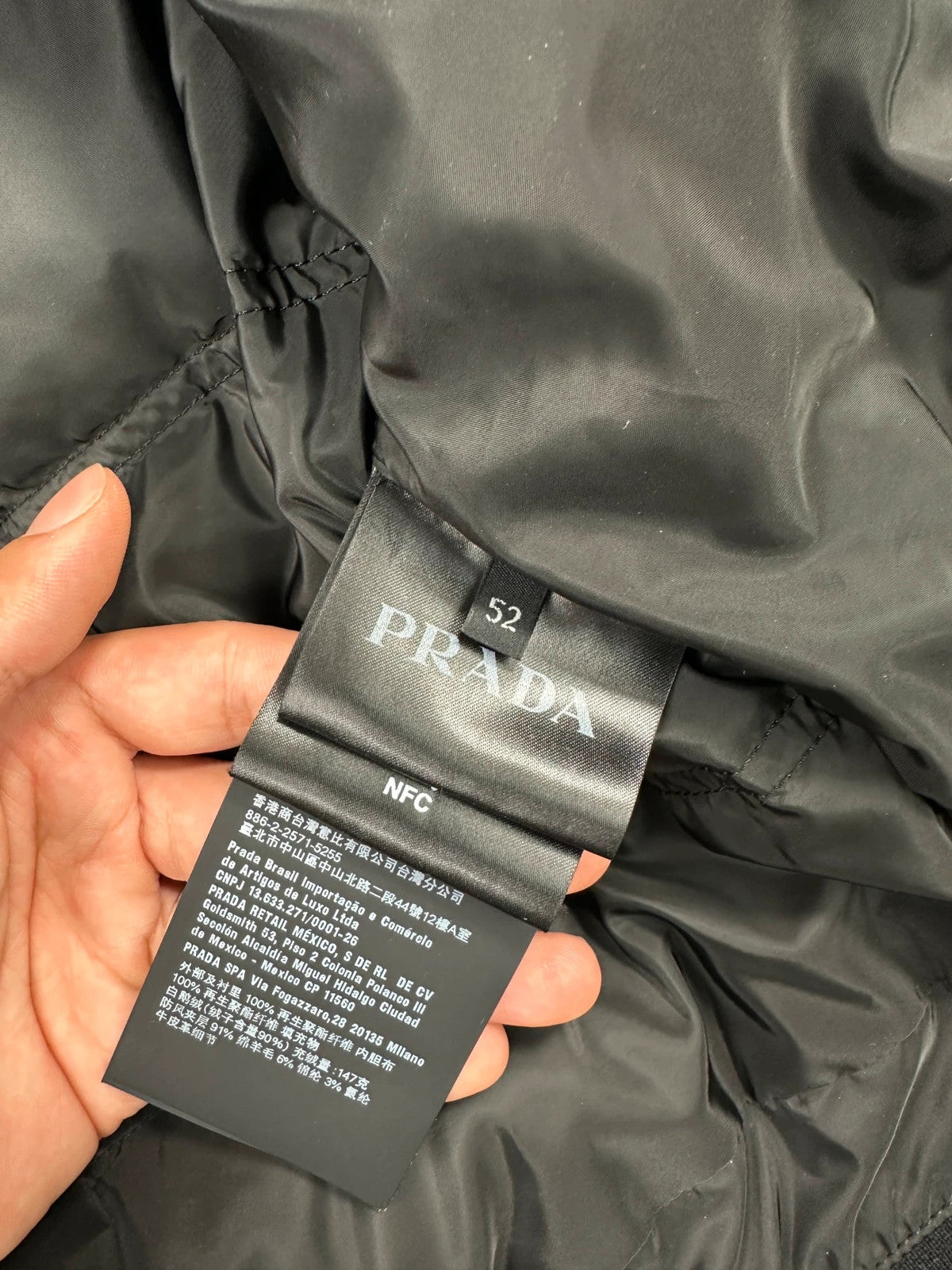 Prada khaki puffer down jacket with hood, featuring triangle logo and luxurious material.