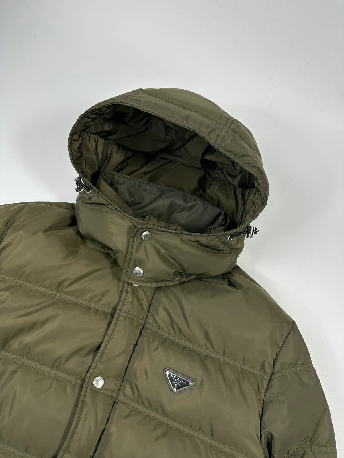 Prada khaki puffer down jacket with hood, featuring triangle logo and luxurious material.