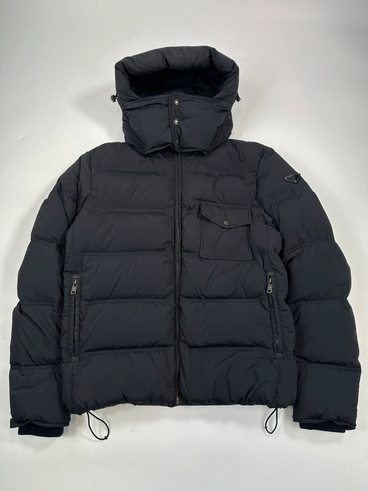 Prada dark navy hooded puffer jacket with triangle logo and vintage 2000s design.