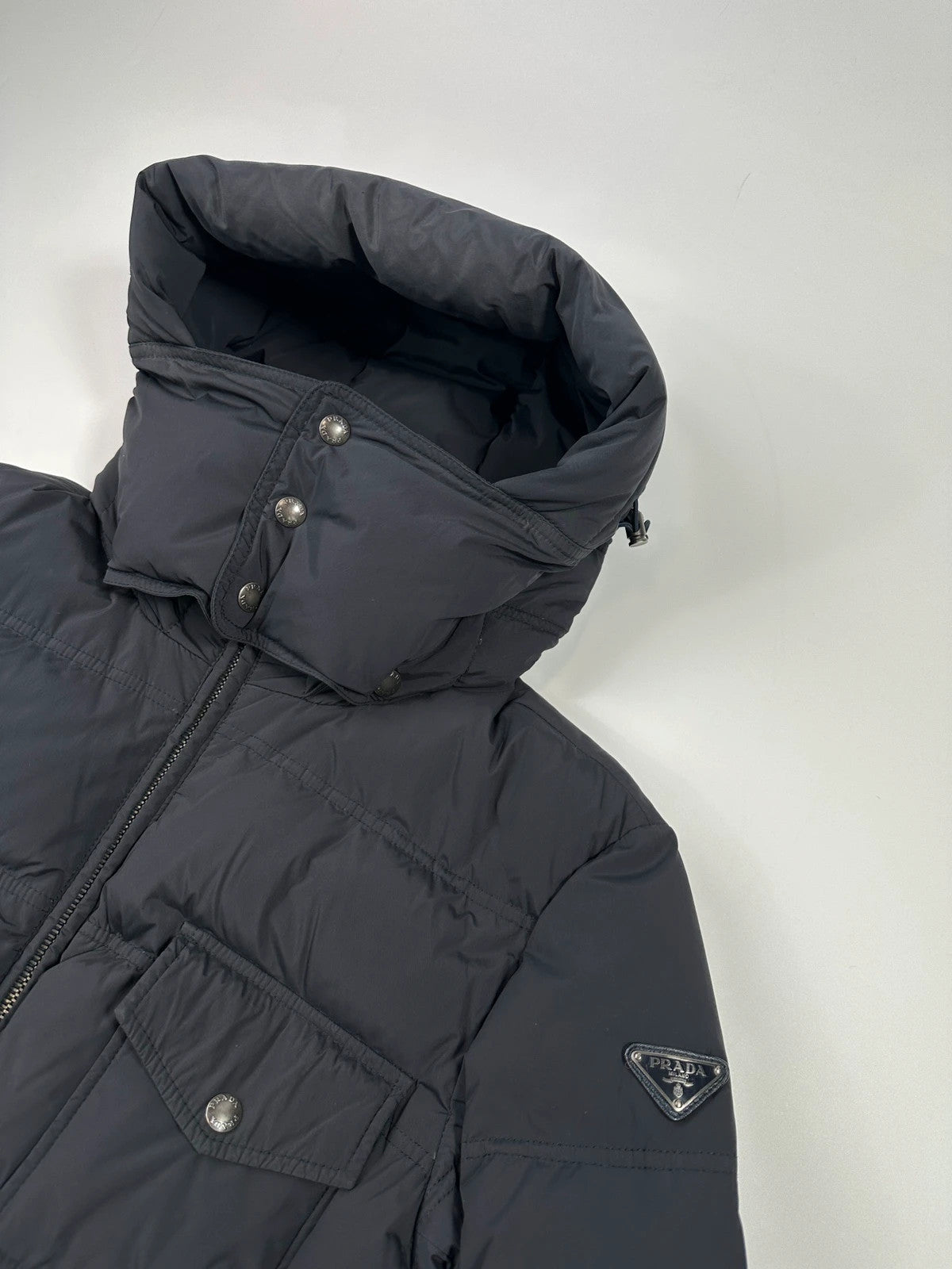 Prada dark navy hooded puffer jacket with triangle logo and vintage 2000s design.